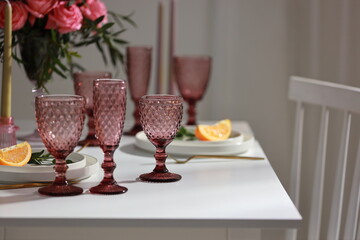 Table setting at wedding reception. Floral compositions with beautiful flowers, lemond and greenery, candles, laying and plates on decorated table