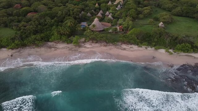 An aerial view of a wavy sea and green forest with gazebos - vaca