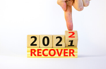 Symbol of planning 2022 recover new year. Businessman turns a wooden cube and changes words 'recover 2021' to 'recover 2022'. Beautiful white background, copy space. Business, 2022 recover concept.