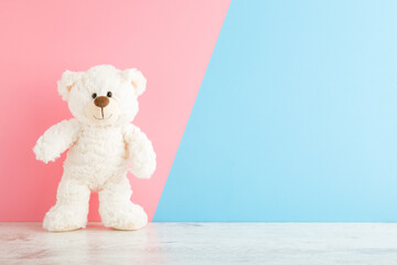 Smiling white teddy bear standing on wooden floor at light pink blue wall background. Pastel color....