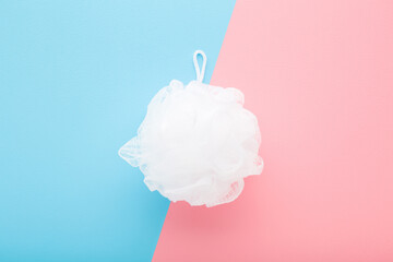White soft shower sponge on light pink blue table background. Pastel color. Product for body...