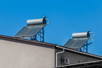Thermal solar panels and water heaters alternative technology of water heating on the roof of the home against the blue sky © Andrey