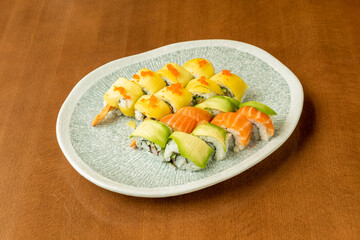 Tray of Different Flavor uramaki Sushi Topped with Norwegian Salmon, Mango Slices and Avocado Slices on Top with Fish Roe, Nori Seaweed and Tempura Shrimp