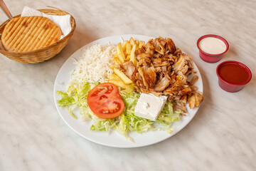 Menu plate chicken kebab with fresh cheese, with cold potatoes, white rice and iceberg lettuce, sliced tomato, sauces and pita bread