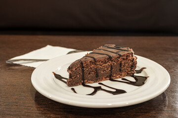Chocolate cake with hot dark chocolate syrup on white plate
