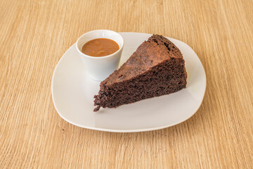 Delicious dessert portion of chocolate cake with hot chocolate syrup in a small white bowl