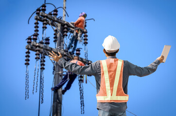 Male electrical engineer raises his hand at a high voltage cable installation site.