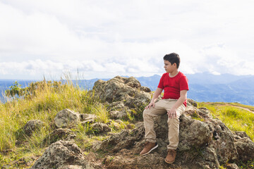 latin boy sitting on the rock looking at the landscape