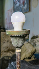 Old lamp in the artist's workshop. White light bulb and metal base.