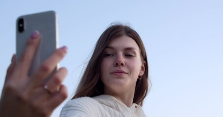 portrait of a young woman with a bionic hand who takes a selfie on a smartphone. a person with disabilities smiles and takes a selfie. new normality, diversity, the concept of modernity and the future