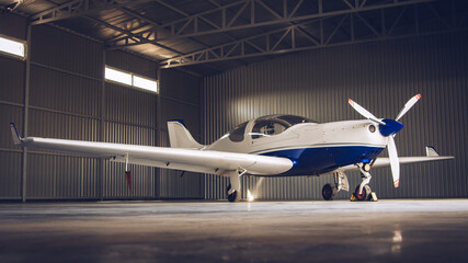 Small white private jet parked in the hangar