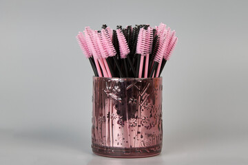 A jar with brushes for eyelashes on a gray background. Cosmetic accessories for eyelash extensions