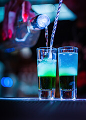 bartender making collection of colorful shots. Set of cocktails at the bar counter