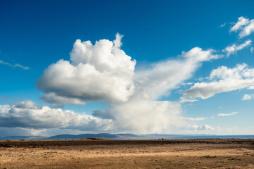 Massive empty field, Atlantic ocean and Burren mountains in the background. Nobody. Warm sunny day, large cloudy sky. Teal and orange colors. Simple Irish nature landscape