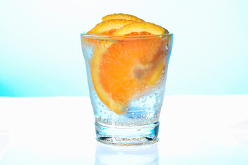 orange slices with bubbles in a misted glass of sparkling water