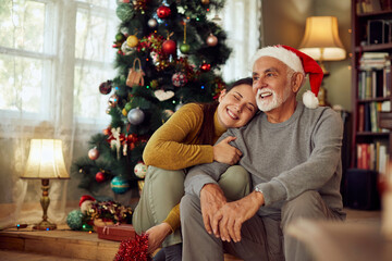 Happy woman embraces her senior father on Christmas day at home. - Powered by Adobe