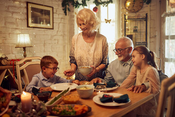 Happy children enjoy in Christmas lunch with their grandparents at home.