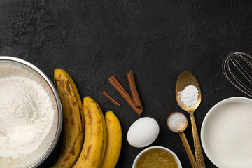 Bulk ingredients for banana bread in bowls and bananas on black background