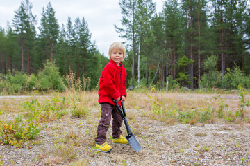 Cute child, digging a hole, cleaning after himself on a wild camping