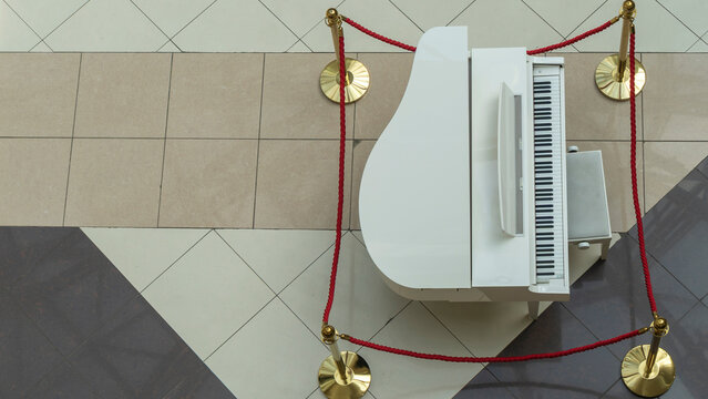 White grand piano in shopping center. Image for design. Space for text.