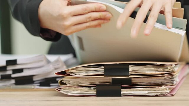 Close-up hand of businesswoman searching for financial and accounting file paperwork in an office file cabinet