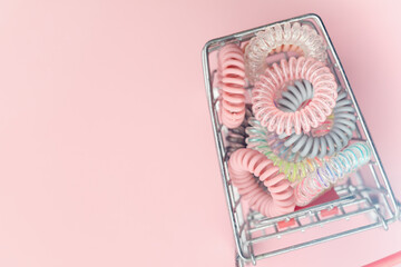 The shopping cart of spiral hair rubber bands on pink background for feminine accessories concept