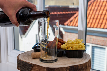 Pouring dark beer  in glass, lunch with with fried cod fish fillet and french fried potatoed chips with view on street in old Zierikzee town, Zeeland, Netherland