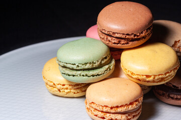 Macarons de colores sobre fondo negro. Concepto gastronomía repostería. 
