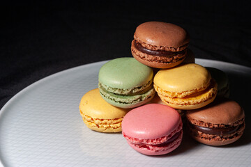 Macarons de colores sobre fondo negro. Concepto gastronomía repostería. 