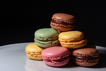 Macarons de colores sobre fondo negro. Concepto gastronomía repostería. 
