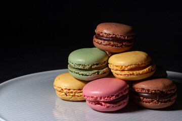 Macarons de colores sobre fondo negro. Concepto gastronomía repostería. 