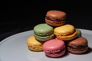 Macarons de colores sobre fondo negro. Concepto gastronomía repostería. 