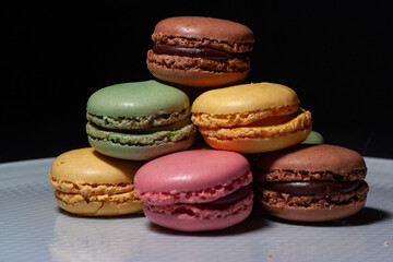 Macarons de colores sobre fondo negro. Concepto gastronomía repostería. 