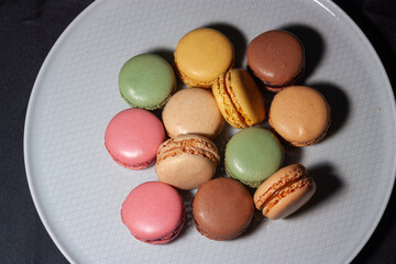 Macarons de colores sobre fondo negro. Concepto gastronomía repostería. 