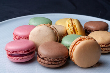 Macarons de colores sobre fondo negro. Concepto gastronomía repostería. 