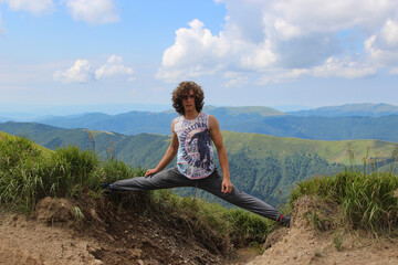 Naklejka na ściany i meble yoga in the mountains, a 16-year-old boy performs a straight split in the mountains