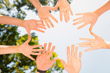 Close up bottom view photo of diverse people holding hands in circle showing unity and support and winning in teamwork.