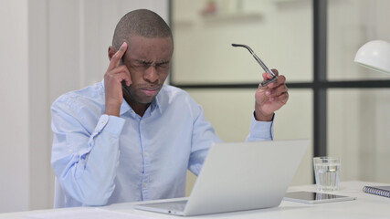 African Man with Headache while Typing on Laptop 