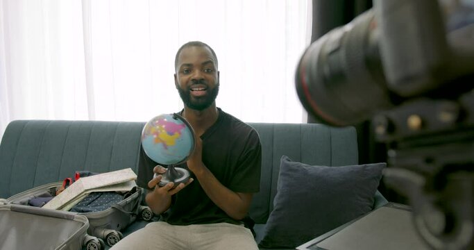 African blogger holding a globe and filming blog
