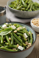 Delicious salad with green beans, pine nuts and cheese on table, closeup