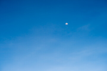 Half moon on blue bright sky background and clear clouds on daytime
