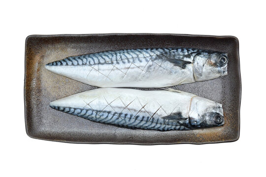 Saba fish cut in half, deer on a brown plate, ready to cook.