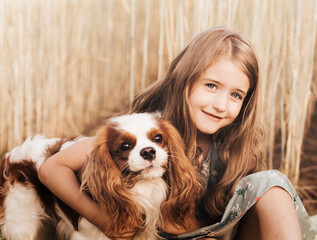 Little girl with a cavalier king charles spaniel dog playing in the summer in nature