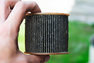 Car mechanic holding in hand old dirty paper fuel filter. Clogged Box diesel fuel filter.