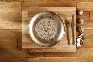 Wooden oak table with golden dishes in a minimalist autumn mood