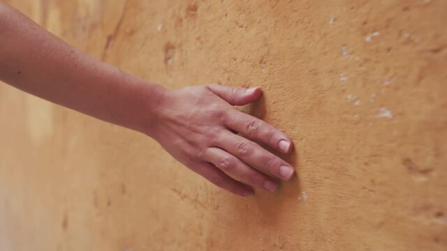 Mano desliz&aacute;ndose por una pared de color naranja o albero