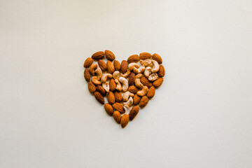 Cashews and almonds are laid out on a white background in the shape of a heart. Proper nutrition, healthy snack. Healthy heart.