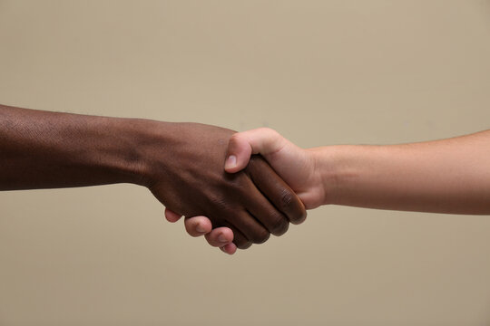 Men shaking hands on beige background, closeup