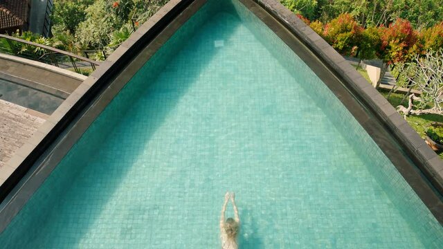 top view sexy woman swimming in infinity pool at tropical hotel spa with view of jungle enjoying luxury lifestyle on exotic summer vacation 4k