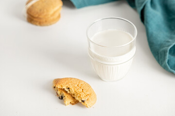 cookies and milk in a glass on a white table with a napkin